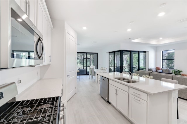 kitchen with appliances with stainless steel finishes, a kitchen island with sink, white cabinetry, and sink