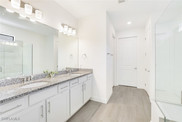 bathroom with a shower with shower door and vanity