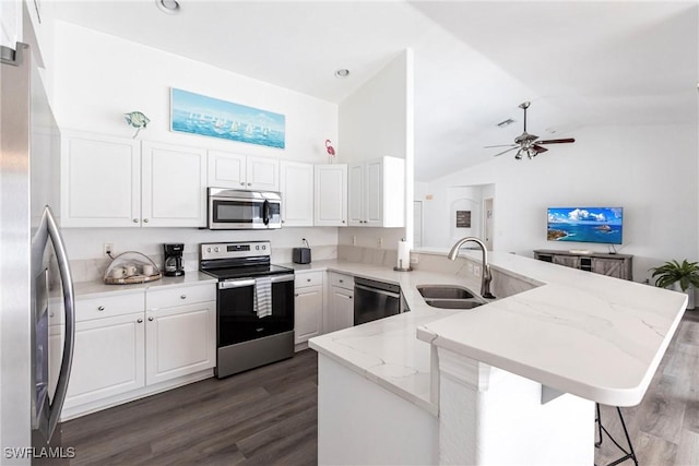 kitchen with kitchen peninsula, appliances with stainless steel finishes, white cabinets, a breakfast bar, and sink