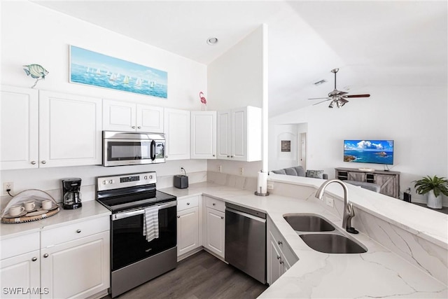 kitchen with lofted ceiling, sink, light stone countertops, appliances with stainless steel finishes, and white cabinets