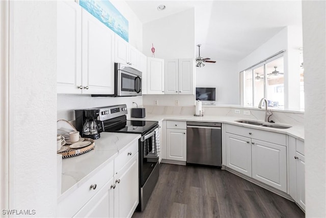 kitchen featuring white cabinetry, appliances with stainless steel finishes, dark hardwood / wood-style flooring, light stone counters, and sink