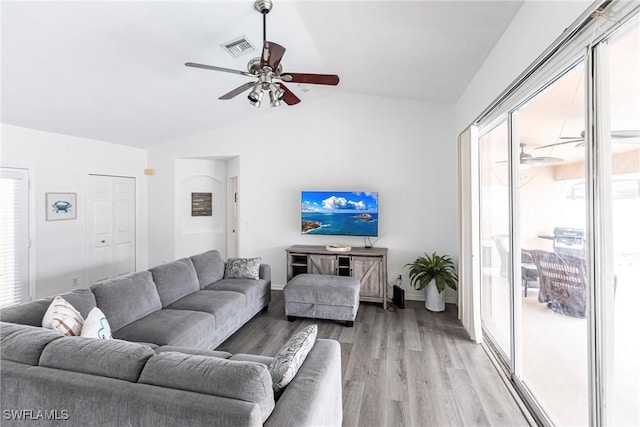 living room with ceiling fan, light wood-type flooring, and vaulted ceiling