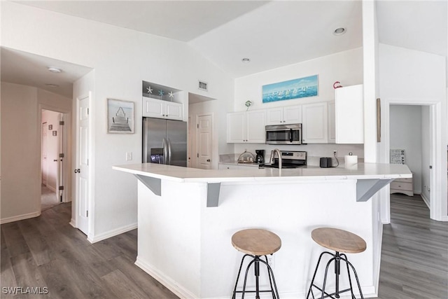 kitchen featuring a breakfast bar, white cabinets, appliances with stainless steel finishes, and kitchen peninsula