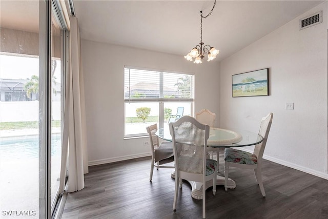 dining area with lofted ceiling, a healthy amount of sunlight, dark wood-type flooring, and an inviting chandelier