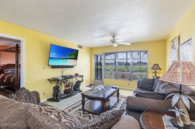 carpeted living room with ceiling fan and a textured ceiling