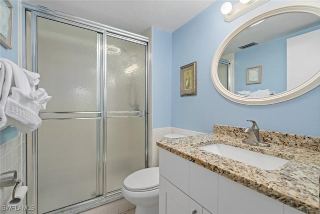 bathroom with toilet, a shower stall, visible vents, and vanity