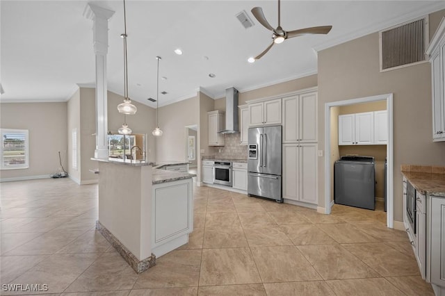 kitchen with decorative light fixtures, white cabinetry, wall chimney range hood, stainless steel appliances, and light stone counters