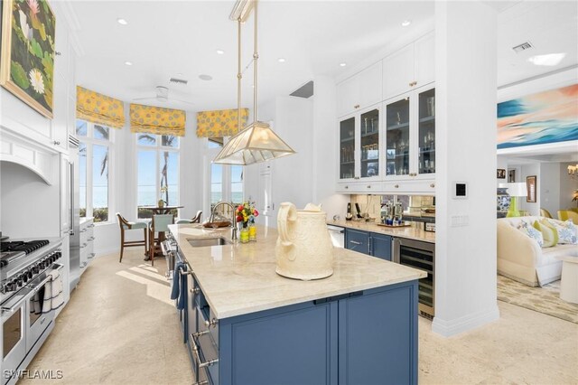 kitchen featuring pendant lighting, range with two ovens, beverage cooler, and blue cabinets