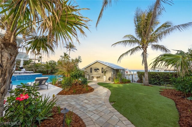 view of front of house featuring a fenced in pool, an outbuilding, and a lawn