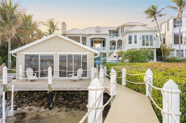 back house at dusk featuring a wooden deck and a sunroom