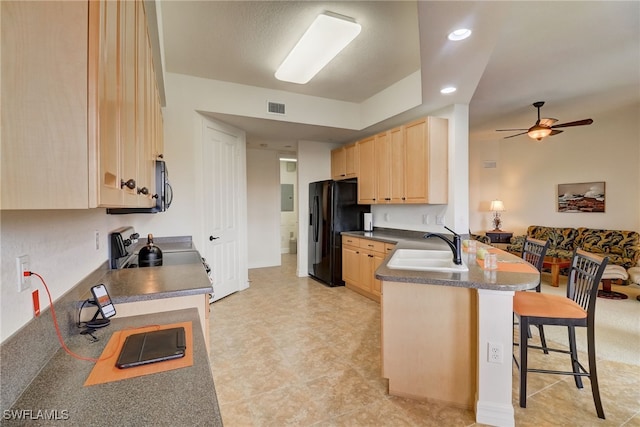 kitchen featuring light brown cabinets, a kitchen breakfast bar, sink, kitchen peninsula, and black fridge with ice dispenser