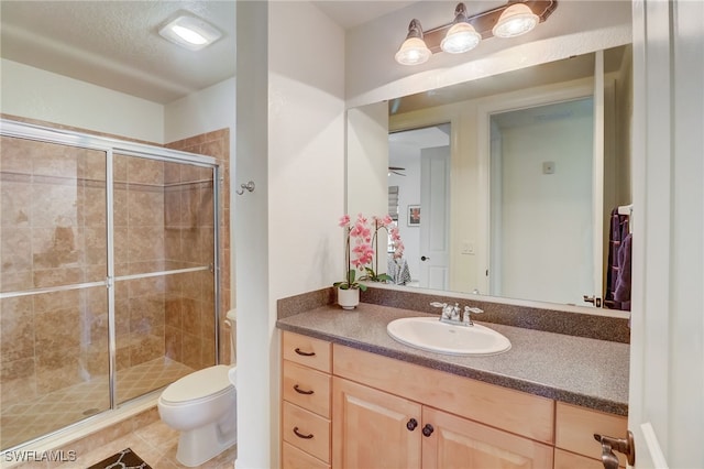 bathroom featuring tile patterned flooring, a shower with door, vanity, toilet, and ceiling fan