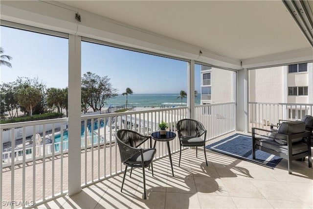 sunroom / solarium featuring a water view and a beach view