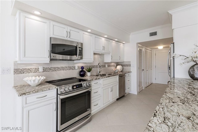 kitchen featuring light stone counters, ornamental molding, appliances with stainless steel finishes, decorative backsplash, and white cabinets