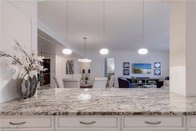 kitchen featuring ornamental molding, white cabinets, light stone counters, and decorative light fixtures