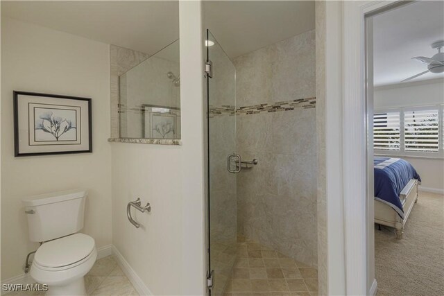 bathroom featuring ceiling fan, a shower with shower door, and toilet