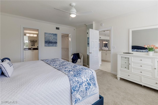 carpeted bedroom with a walk in closet, ensuite bath, ornamental molding, a closet, and ceiling fan