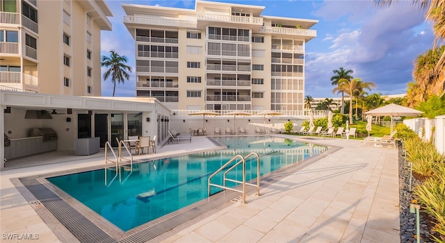 view of pool with area for grilling, a grill, and a patio