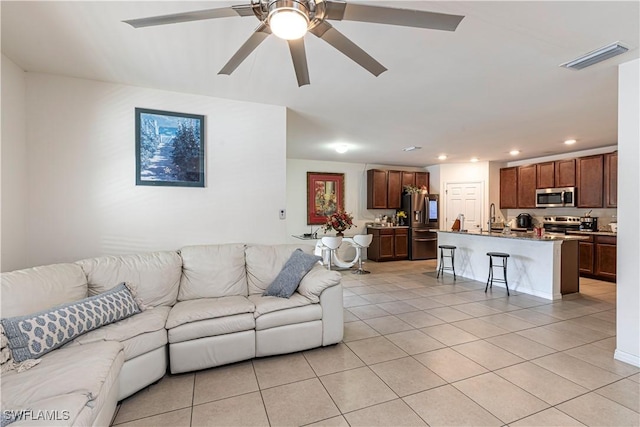 living room featuring ceiling fan, light tile patterned floors, and sink