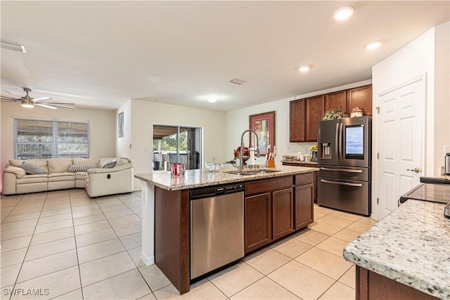 kitchen featuring light stone countertops, appliances with stainless steel finishes, sink, a kitchen island with sink, and light tile patterned floors