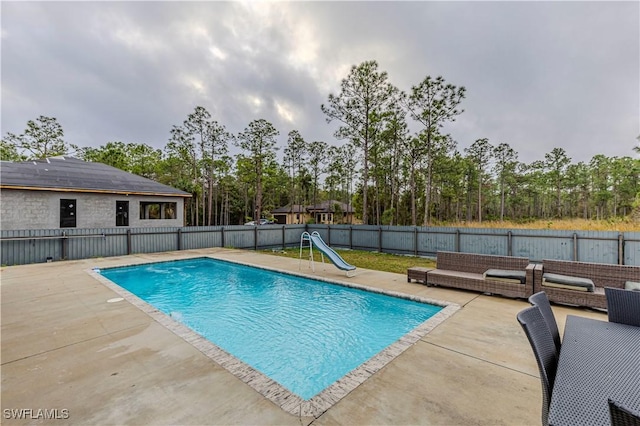 view of pool with outdoor lounge area, a water slide, and a patio