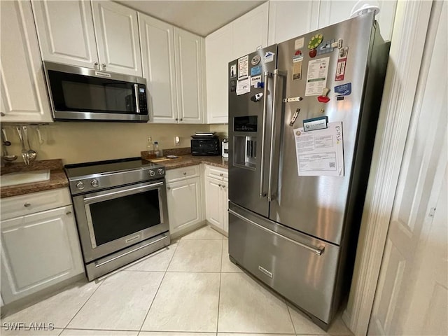 kitchen featuring high end appliances, white cabinetry, and light tile patterned flooring