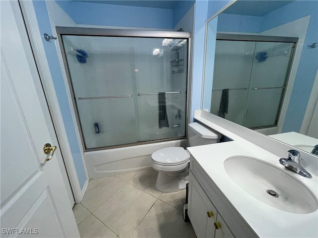 full bathroom with bath / shower combo with glass door, toilet, vanity, and tile patterned flooring