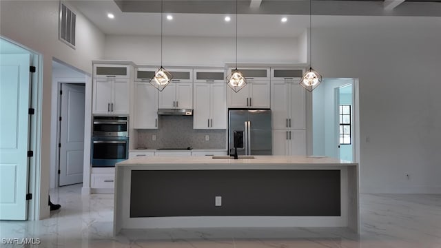 kitchen featuring hanging light fixtures, decorative backsplash, a kitchen island with sink, and stainless steel appliances