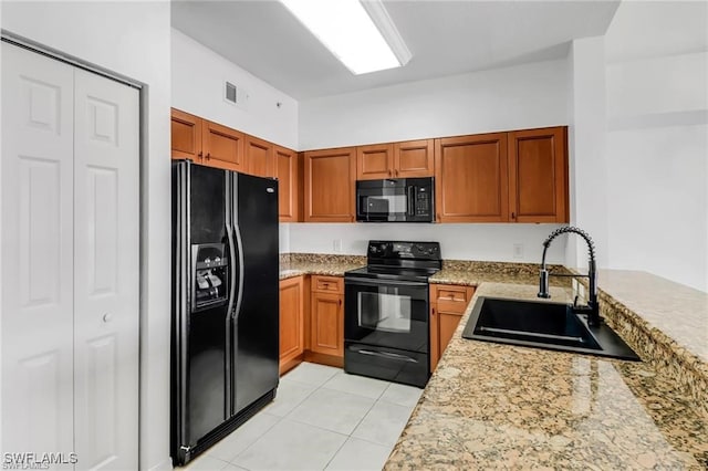 kitchen featuring sink, black appliances, light tile patterned floors, and light stone countertops