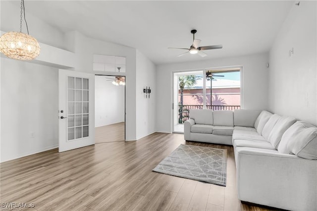 living room featuring wood-type flooring and ceiling fan with notable chandelier