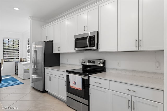 kitchen with appliances with stainless steel finishes, white cabinets, ornamental molding, light tile patterned floors, and light stone countertops