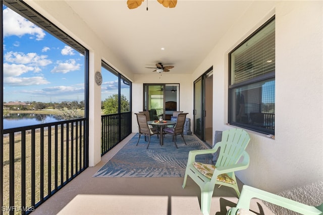 sunroom featuring ceiling fan and a water view