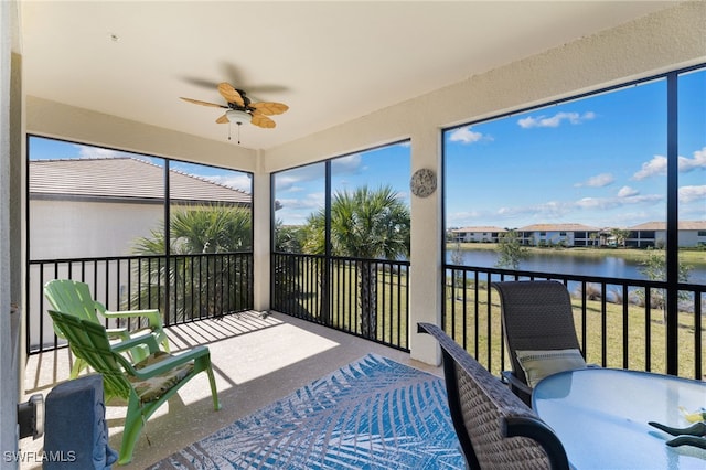 sunroom / solarium with plenty of natural light, ceiling fan, and a water view