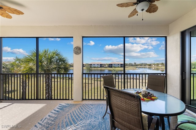 sunroom with plenty of natural light, ceiling fan, and a water view