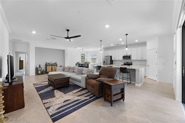 tiled living room featuring crown molding, sink, and ceiling fan