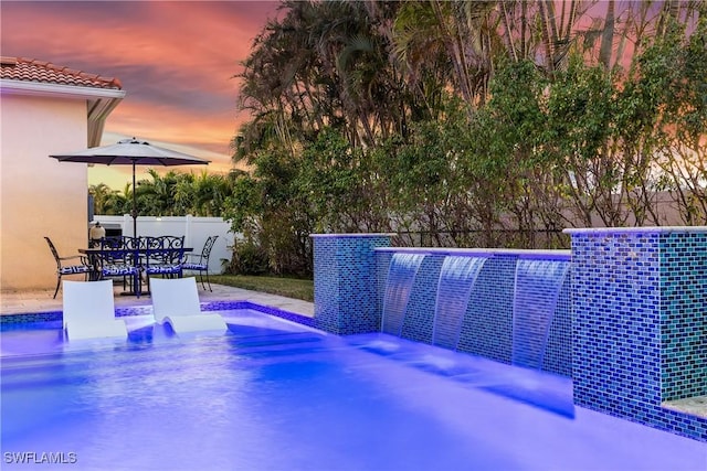 pool at dusk featuring a patio