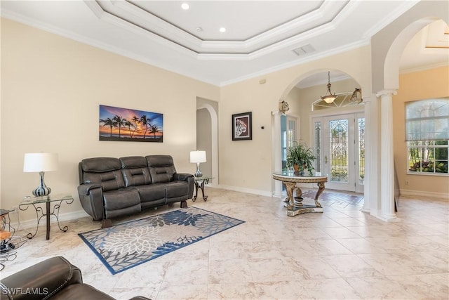 living room with ornate columns, crown molding, and a tray ceiling