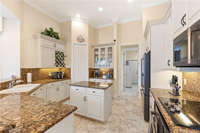 kitchen with white cabinetry, a center island, dark stone counters, black appliances, and sink