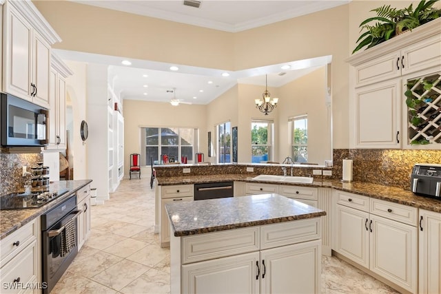 kitchen with kitchen peninsula, backsplash, a kitchen island, black appliances, and sink