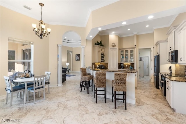 kitchen featuring a high ceiling, white cabinetry, dark stone counters, hanging light fixtures, and a notable chandelier