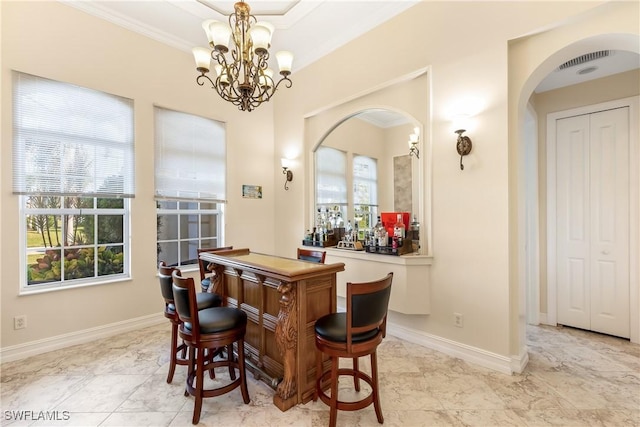 dining space featuring bar, a chandelier, and crown molding