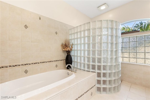 bathroom with tiled bath and tile patterned floors