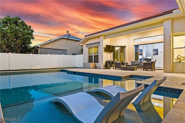 pool at dusk with an outdoor living space and a patio area