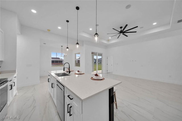 kitchen featuring white cabinetry, appliances with stainless steel finishes, a raised ceiling, a kitchen island with sink, and sink