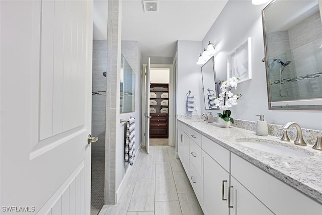 bathroom with tiled shower and vanity