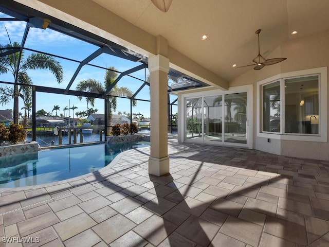 view of swimming pool featuring ceiling fan, a patio area, glass enclosure, and a water view