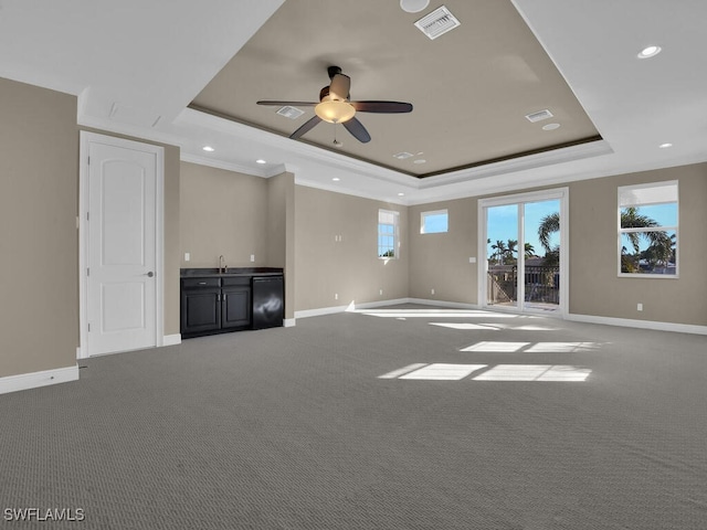 unfurnished living room featuring ceiling fan, carpet flooring, and a tray ceiling