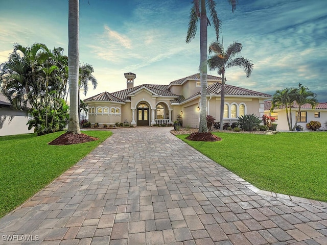 mediterranean / spanish-style house featuring a garage and a front lawn