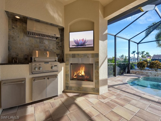 view of patio / terrace featuring exterior kitchen, grilling area, a tiled fireplace, and glass enclosure