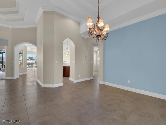 empty room with a towering ceiling, a chandelier, a tray ceiling, crown molding, and tile patterned floors